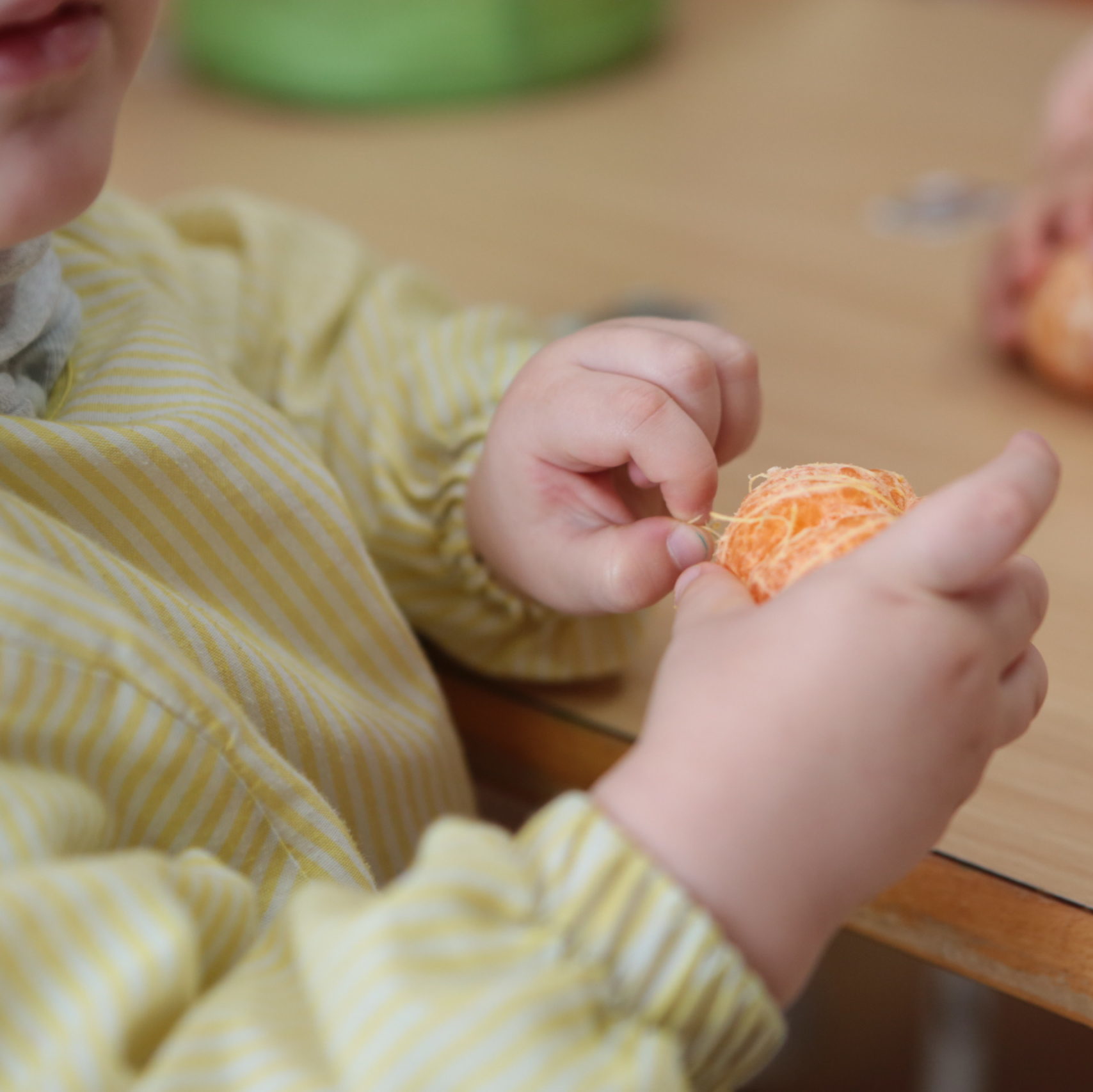 niño pelando una mandarina en Escuelas Infantil Lápices